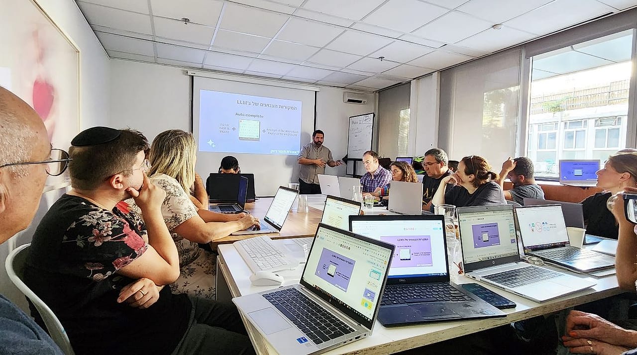 בן רוטנברג מעביר סדנת AI מעשית סביב שולחן מלא לפטופים